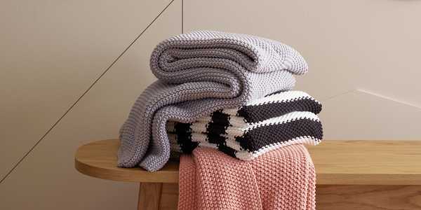 Blankets stacked on wooden bench.
